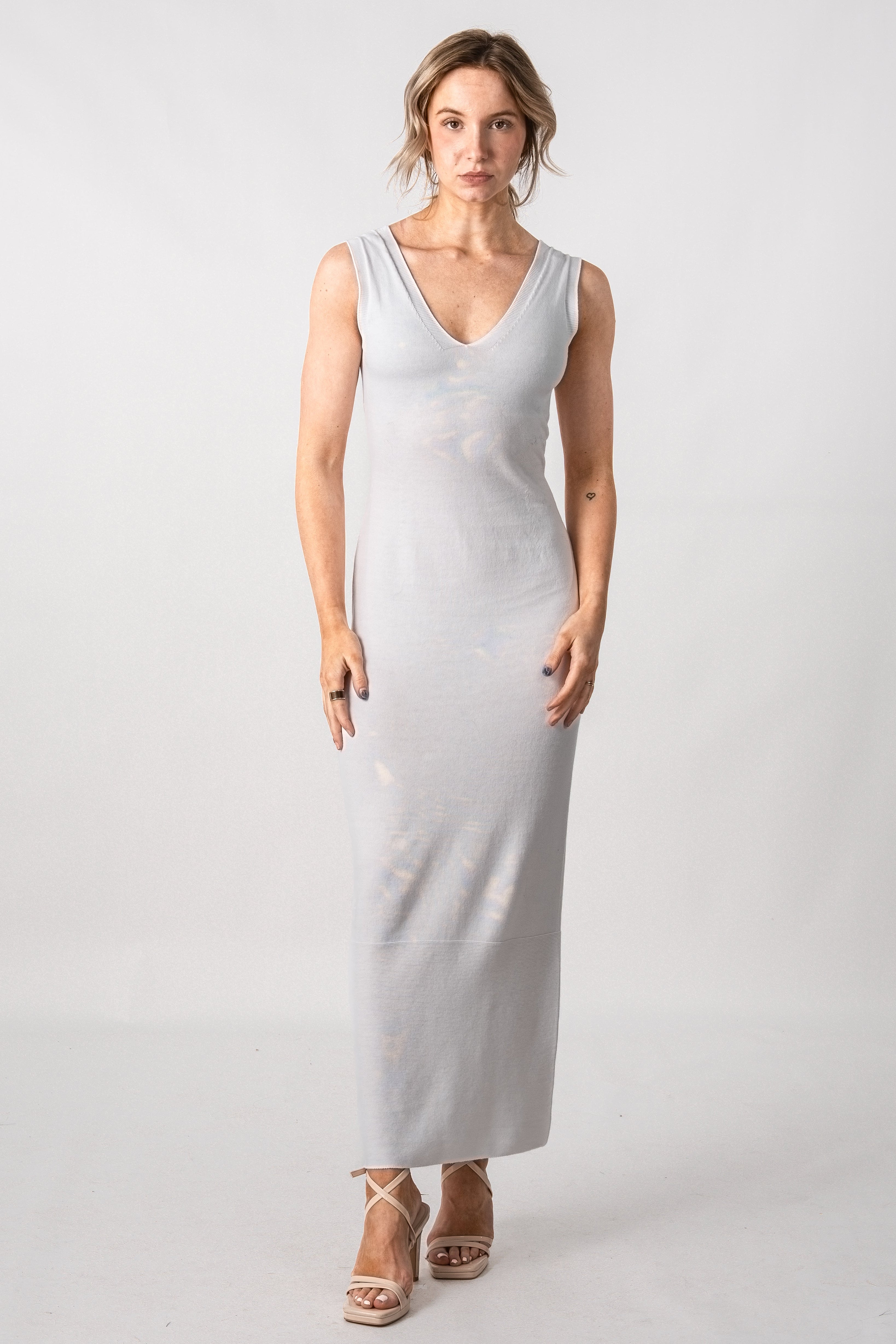 Woman wearing a white sleeveless dress against a plain background