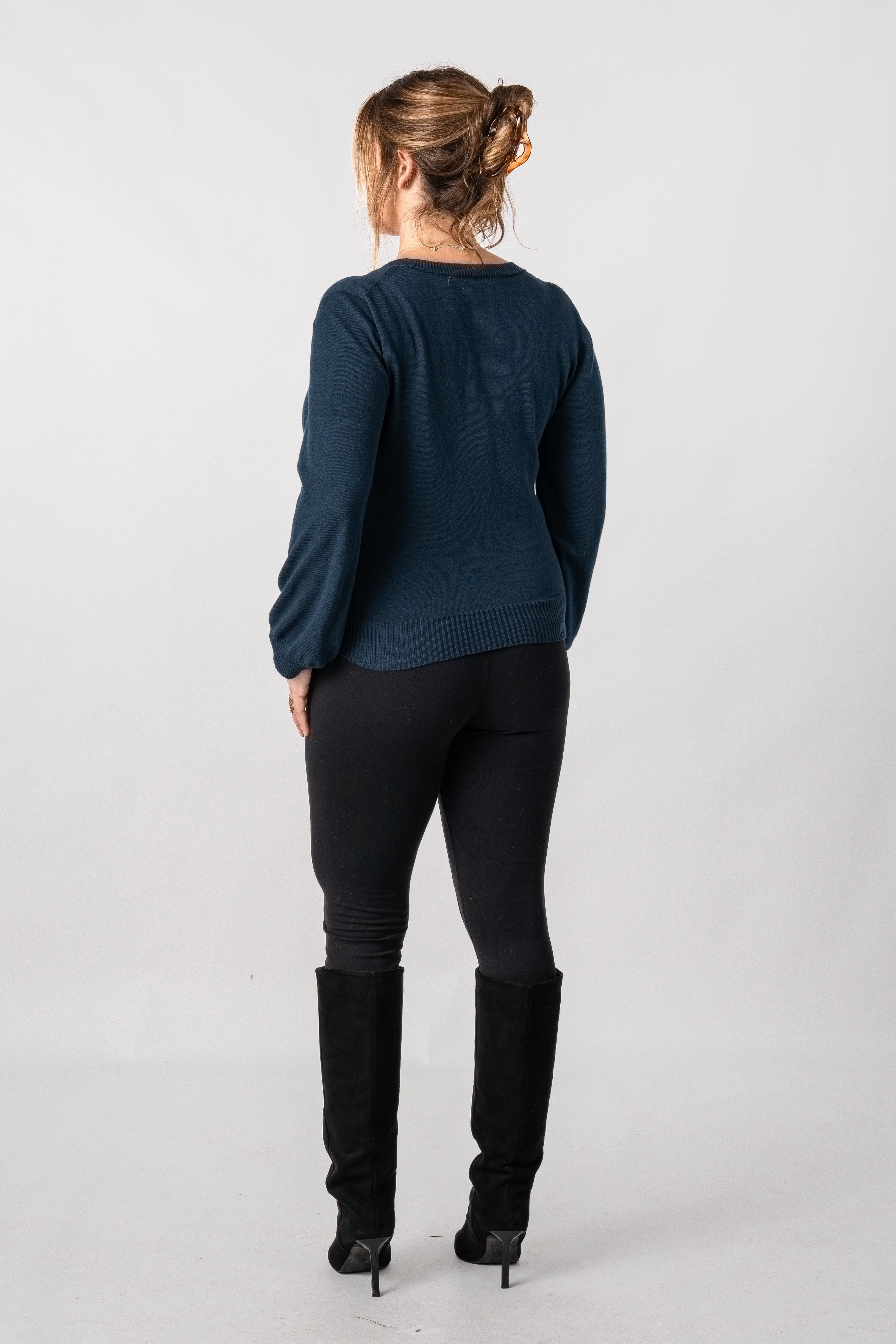 Woman wearing a dark blue sweater and black pants on a white background