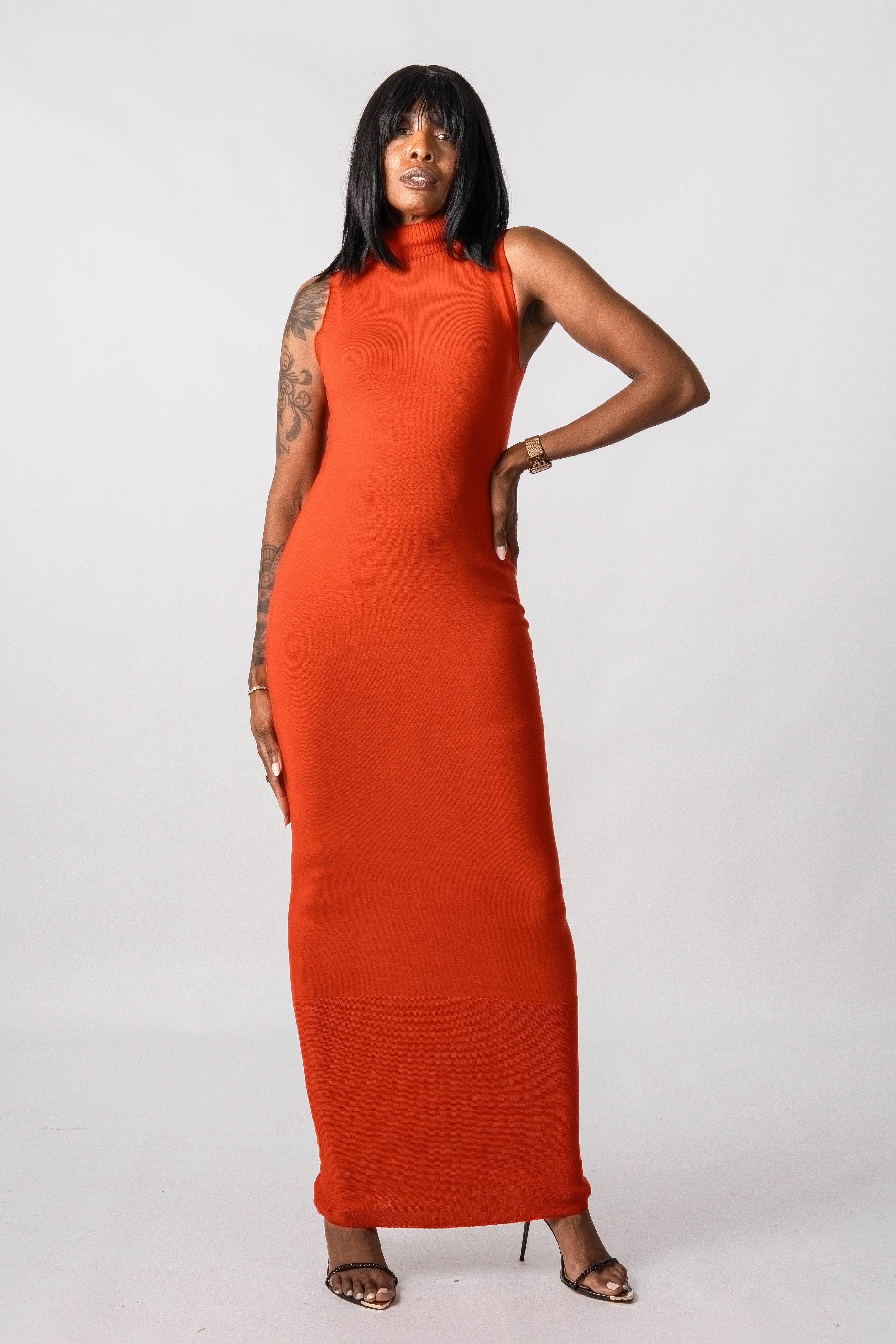 Woman wearing a long orange dress against a white background