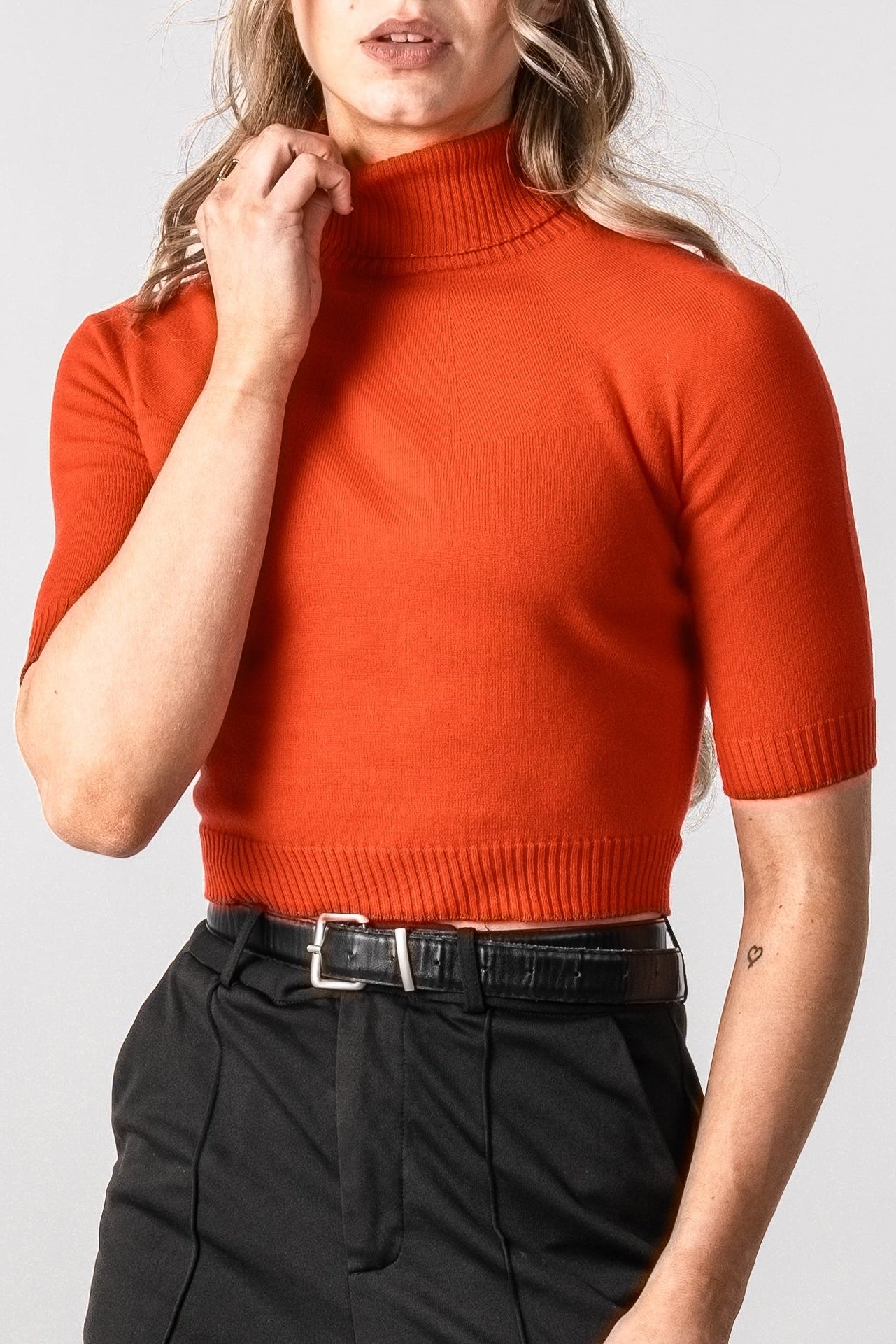 Woman wearing a red top and black pants on a white background