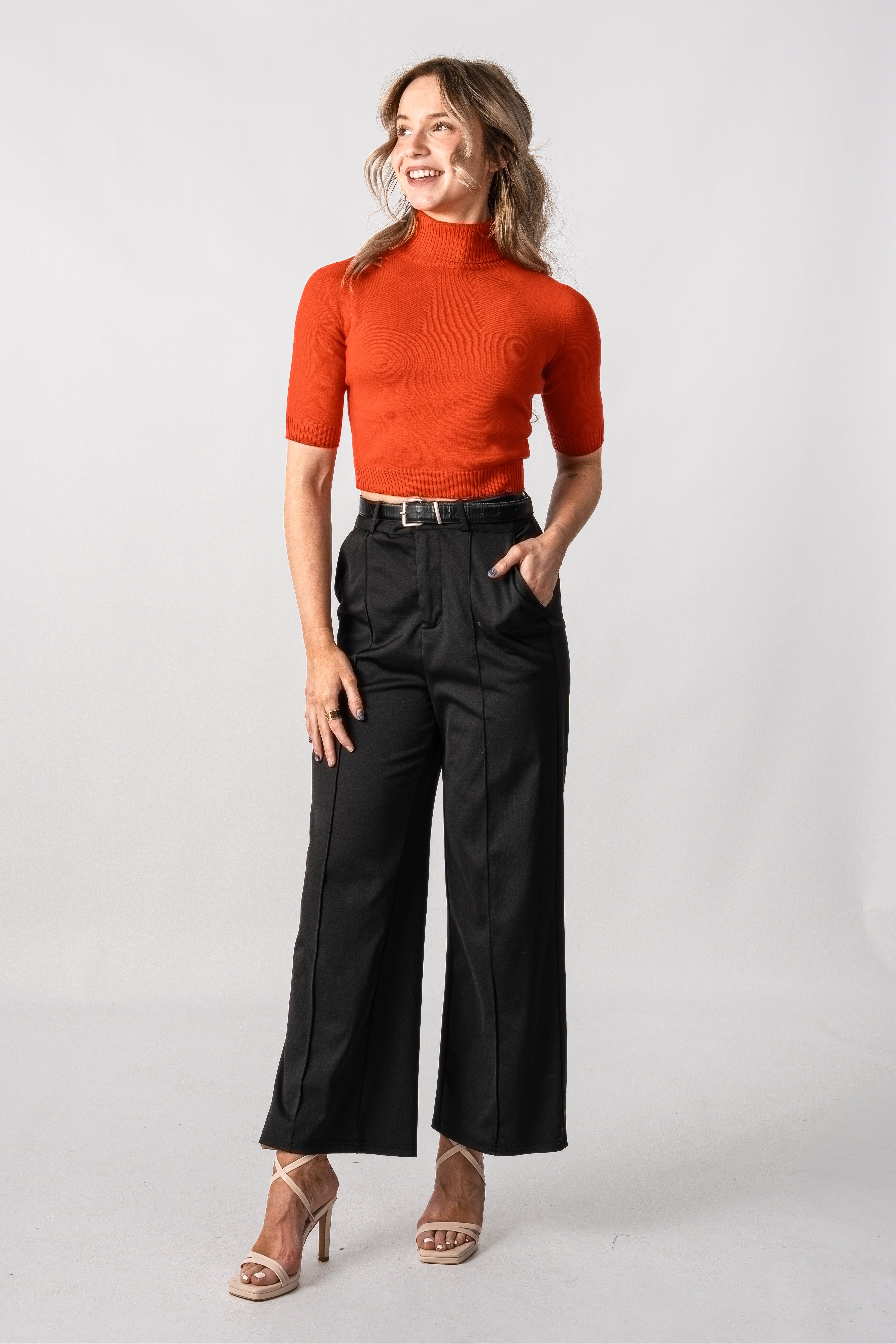 Woman wearing a red top and black pants on a white background