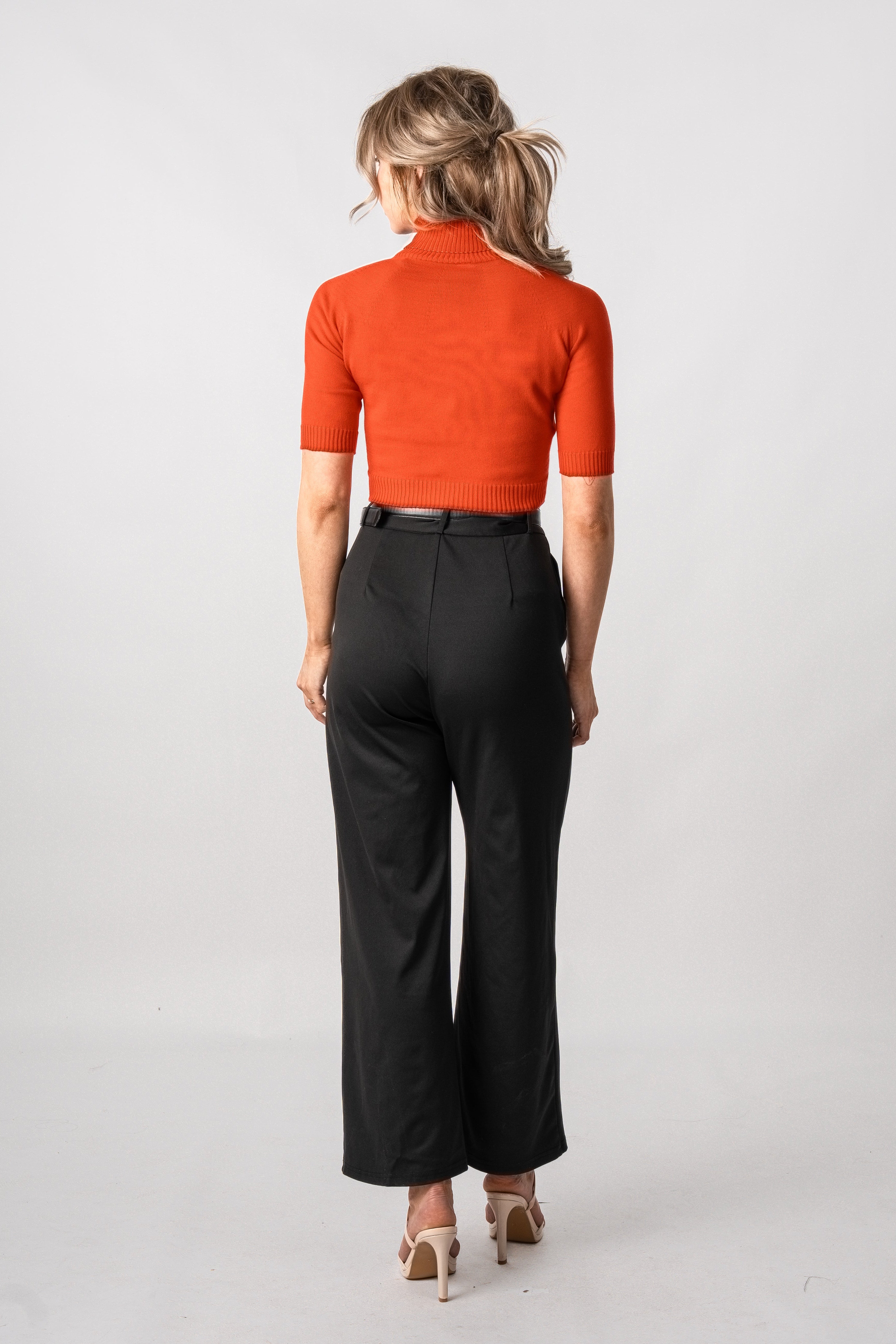 Woman wearing a red top and black pants on a white background